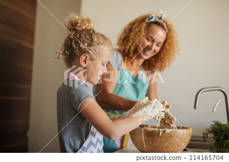 Woman and cute daughter cooking on kitchen, making dough for birthday party. Woman and cute daughter cooking on kitchen, making dough for birthday party. 114165704