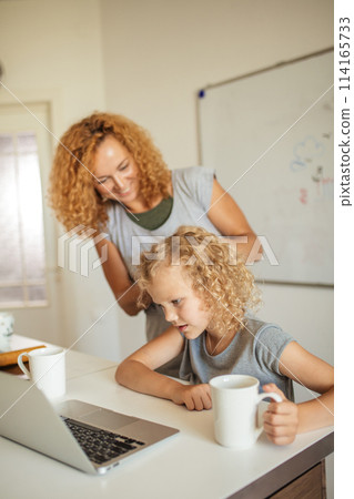 Smiling Mother helps her adorable daughter with homework 114165733
