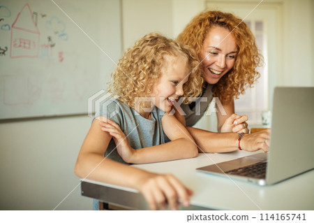 Smiling Mother helps her adorable daughter with homework 114165741