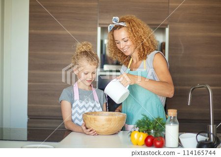 Little daughter helping mother baking in kitchen, family and cooking 114165744
