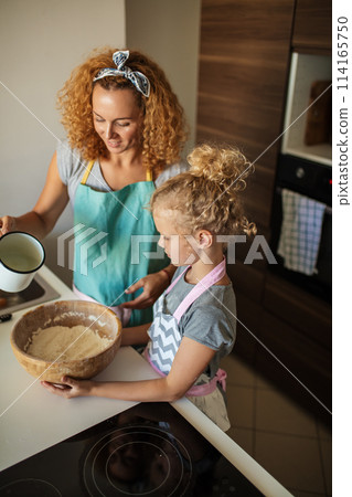 Little daughter helping mother baking in kitchen, family and cooking Little daughter helping mother baking in kitchen, family and cooking 114165750