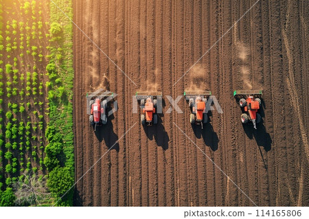 Aerial shots of Farmers operating tractors equipped with seed drills. 114165806