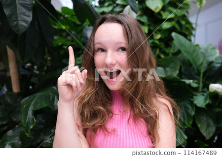 The girl raised her hand with her index finger raised, her mouth open, she was very surprised, I came up with. High quality photo 114167489
