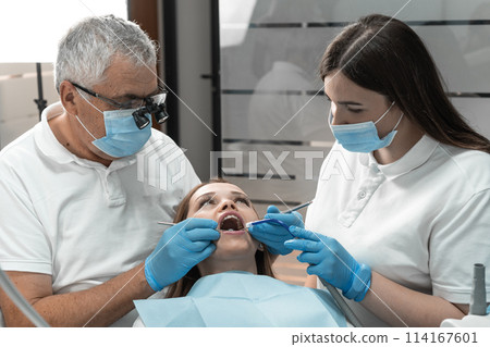 In the process of treating the patient's teeth, the dentist demonstrates high accuracy and attentiveness. She monitors every stage, guaranteeing high-quality restoration health and beauty of a smile. 114167601