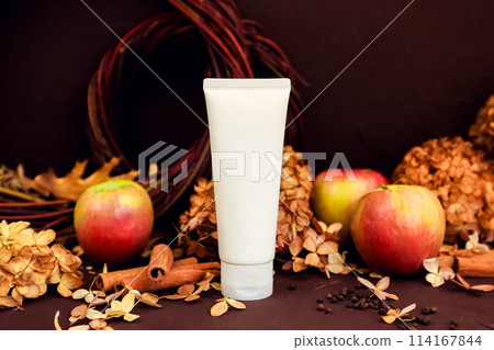 cosmetic moisturizer cream in white tube bottle, apples, cinnamon, dried flowers on brown. Body cream, gel, skincare, hand creme, shampoo, hair conditioner or packaging mockup in autumn composition. cosmetic moisturizer cream in white tube bottle, apples, cinnamon, dried flowers on brown. Body cream, gel, skincare, hand creme, shampoo, hair conditioner or packaging mockup in autumn composition. 114167844