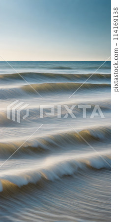 Smoothly blurred sky over a sun-kissed calm sea, golden sands of a tranquil beach in the foreground 114169138