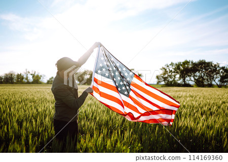 Man hold waving american USA flag. Patriot raise national american flag. Independence Day, 4th July. Man hold waving american USA flag. Patriot raise national american flag. Independence Day, 4th July. 114169360