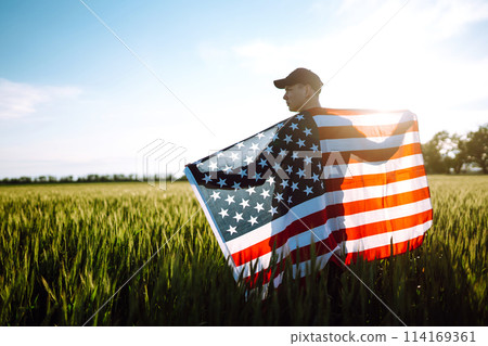 Man hold waving american USA flag. Patriot raise national american flag. Independence Day, 4th July. Man hold waving american USA flag. Patriot raise national american flag. Independence Day, 4th July. 114169361