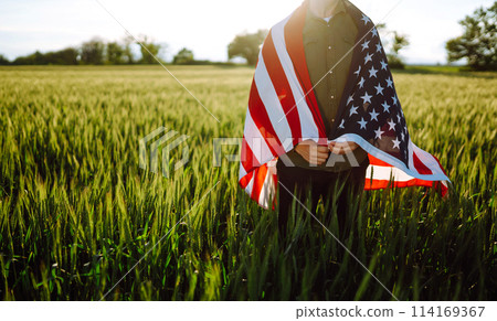 Man hold waving american USA flag. Patriot raise national american flag. Independence Day, 4th July. Man hold waving american USA flag. Patriot raise national american flag. Independence Day, 4th July. 114169367