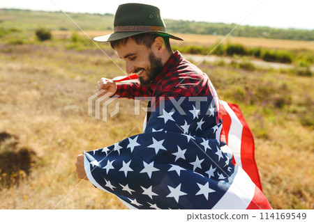 4th of July. American Flag. Traveler with the flag of America. The man in a hat, a backpack, a shirt and jeans. 4th of July. American Flag. Traveler with the flag of America. The man in a hat, a backpack, a shirt and jeans. 114169549