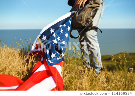 4th of July. American Flag.Patriotic holiday. Traveler with the flag of America. Beautiful sunset light. American style. 4th of July. American Flag.Patriotic holiday. Traveler with the flag of America. Beautiful sunset light. American style. 114169554