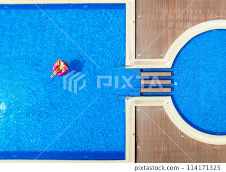 Aerial view of young woman on swimming ring in pool in summer Aerial view of young woman on swimming ring in pool in summer 114171325