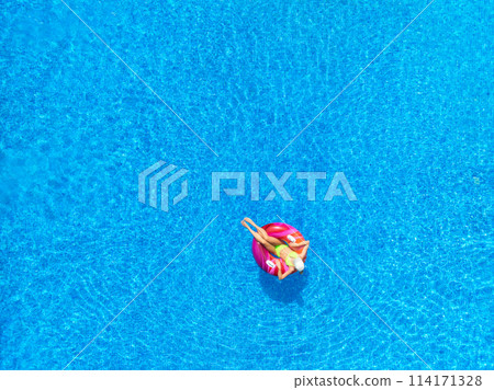 Aerial view of young woman on swimming ring in pool in summer Aerial view of young woman on swimming ring in pool in summer 114171328