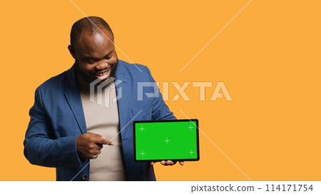 Upbeat african american man holding green screen tablet, doing recommendation. Cheerful BIPOC person pointing towards mockup device, giving positive feedback, studio background, camera A Upbeat african american man holding green screen tablet, doing recommendation. Cheerful BIPOC person pointing towards mockup device, giving positive feedback, studio background, camera A 114171754