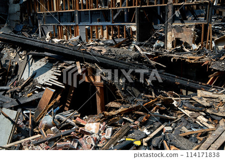 A burnt-out old wooden building after a fire. Charred beams after the destruction 114171838