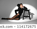 Beautiful woman in retro style in a black bodysuit and a bow in her hair in full length posing on a gray background. Beauty of body and face 114172675
