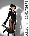 Beautiful woman in retro style in a black bodysuit and a bow in her hair in full length posing on a gray background. Beauty of body and face 114172676