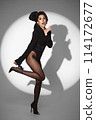 Beautiful woman in retro style in a black bodysuit and a bow in her hair in full length posing on a gray background. Beauty of body and face 114172677