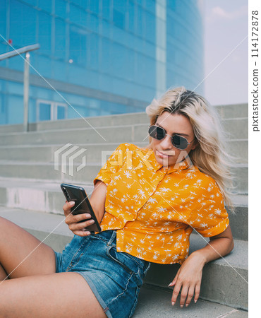 Trendy female with smartphone lying on city stairway Trendy female with smartphone lying on city stairway 114172878