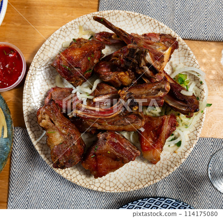 There is plate with cooked lamb barbecue shashlik on wooden table. Pieces of lamb fried on open fire There is plate with cooked lamb barbecue shashlik on wooden table. Pieces of lamb fried on open fire 114175080