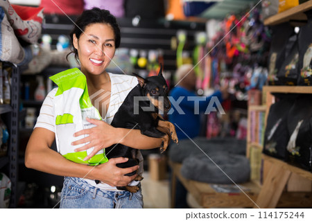 Woman with her dog and package of dog food in pet shop Woman with her dog and package of dog food in pet shop 114175244