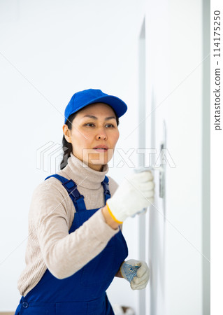 Woman applying plaster to a wall with floated trowel Woman applying plaster to a wall with floated trowel 114175250
