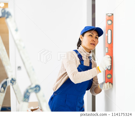 Woman worker measuring wall with spirit level 114175324