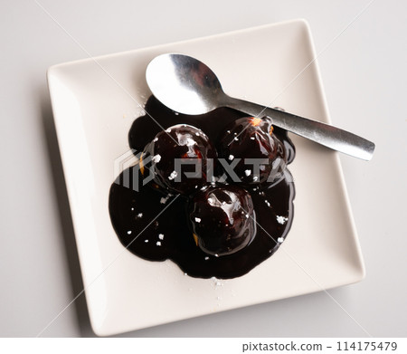 Three small profiteroles, liberally sprinkled with chocolate glaze 114175479