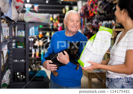 Saleswoman consulting old man about dog food in pet shop 114175481