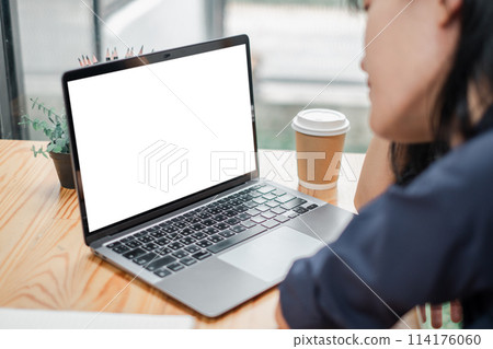 Businesswoman focused on a blank screen laptop in a modern workspace with a coffee cup. Businesswoman focused on a blank screen laptop in a modern workspace with a coffee cup. 114176060