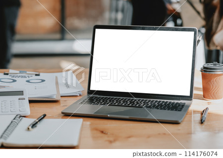 organized workspace featuring an open laptop with a blank screen, a coffee cup, and documents with graphs and data. organized workspace featuring an open laptop with a blank screen, a coffee cup, and documents with graphs and data. 114176074