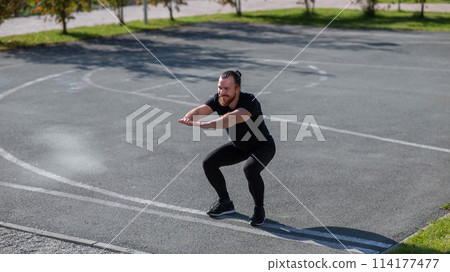 Bearded man doing exercises outdoors.  114177477