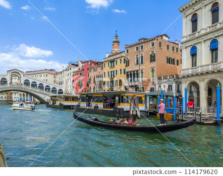 Traditional rowing boat on a canal in front of the Rialto Bridge, Venice, Italy 114179620