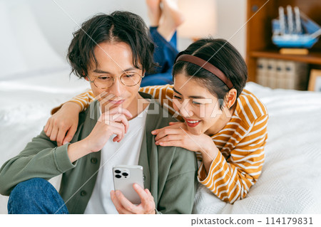 A couple relaxing and looking at their smartphones 114179831