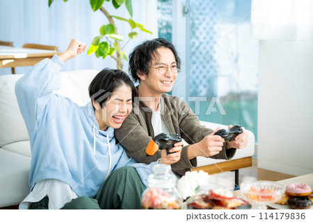 Couple playing games in the living room 114179836