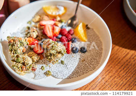 A mixture of strawberries, blueberries, and granola on a plate 114179921