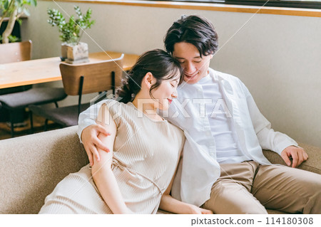 一對友善的年輕亞洲夫婦坐在自家客廳的沙發上 114180308
