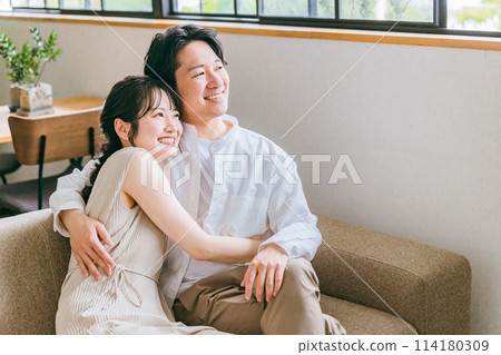 一對友善的年輕亞洲夫婦坐在自家客廳的沙發上 114180309