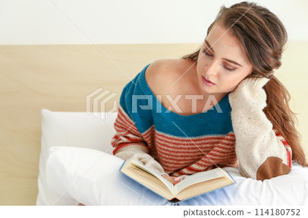 Teenager reads a book resting on her hand Teenager reads a book resting on her hand 114180752