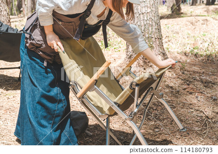 A female camper preparing and packing up a folding outdoor chair during camping/chairing 114180793