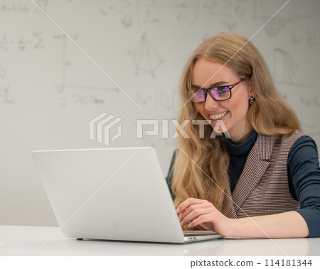 Caucasian woman scientist typing on laptop. White board with formulas. Caucasian woman scientist typing on laptop. White board with formulas. 114181344