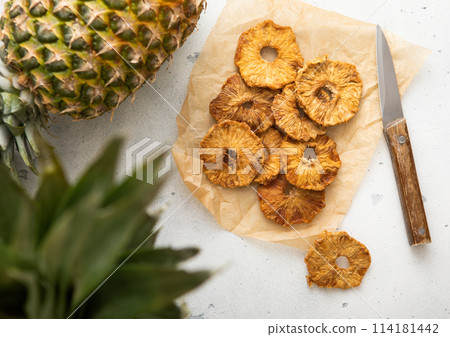 Organic sweet pineapple circle slices on in baking paper with knife on light table. Organic sweet pineapple circle slices on in baking paper with knife on light table. 114181442