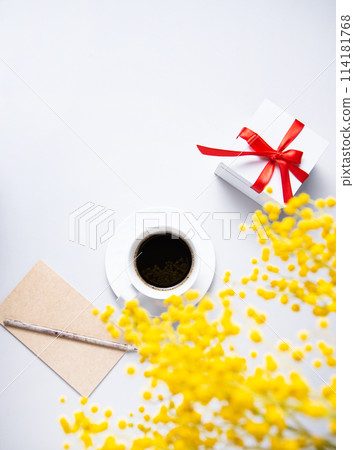 a spring bouquet with yellow mimosa flowers over a cup of black coffee, present box  114181768