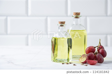 natural dietary and vegan grape seed oil in glass bottles on a white marble background.  114181842