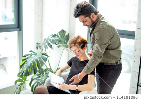 Two business people in discussing information and taking notes as they work together as team 114181886