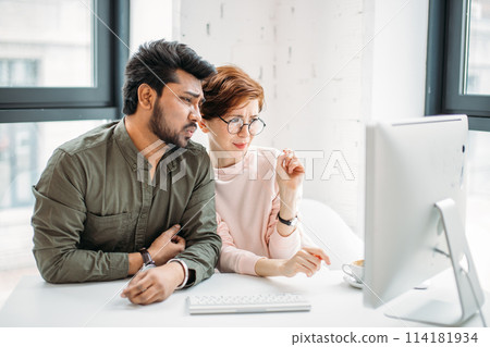 business man and woman colleagues looking at computer trying to solve problems in office 114181934
