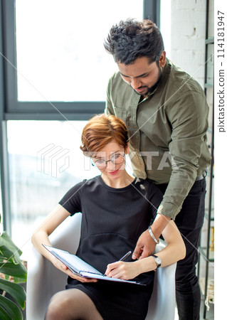 Two business people in discussing information and taking notes as they work together as team 114181947