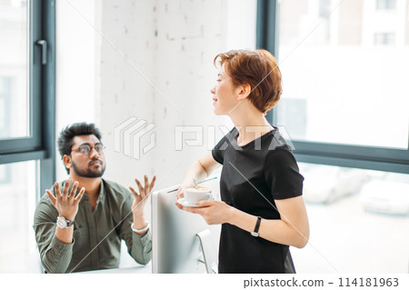 mentor boss smiling looking at young male coworker and drink coffee, teaching helping colleague mentor boss smiling looking at young male coworker and drink coffee, teaching helping colleague 114181963