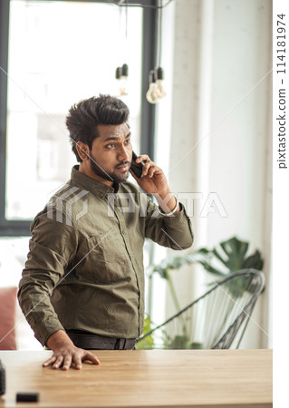 Indian business man talking on phone in modern office 114181974