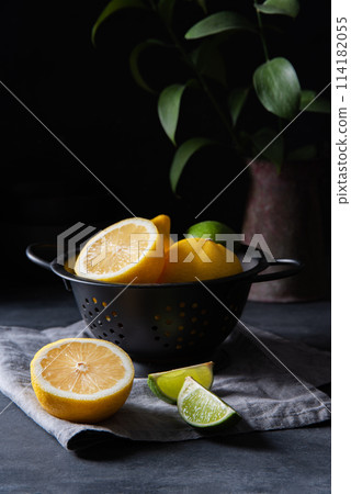 juicy lemons and limes in a black bowl on a gray table. Dark and mood concept juicy lemons and limes in a black bowl on a gray table. Dark and mood concept 114182055